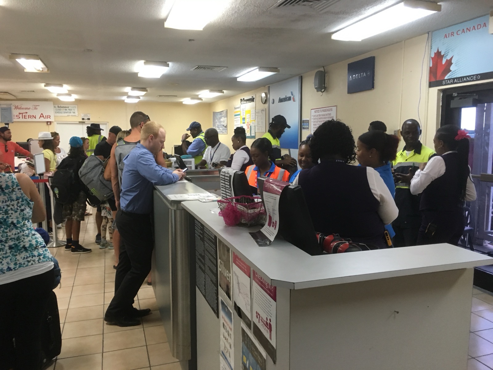 Passenger check-in counters at Exuma International Airport with a queue and airline staff