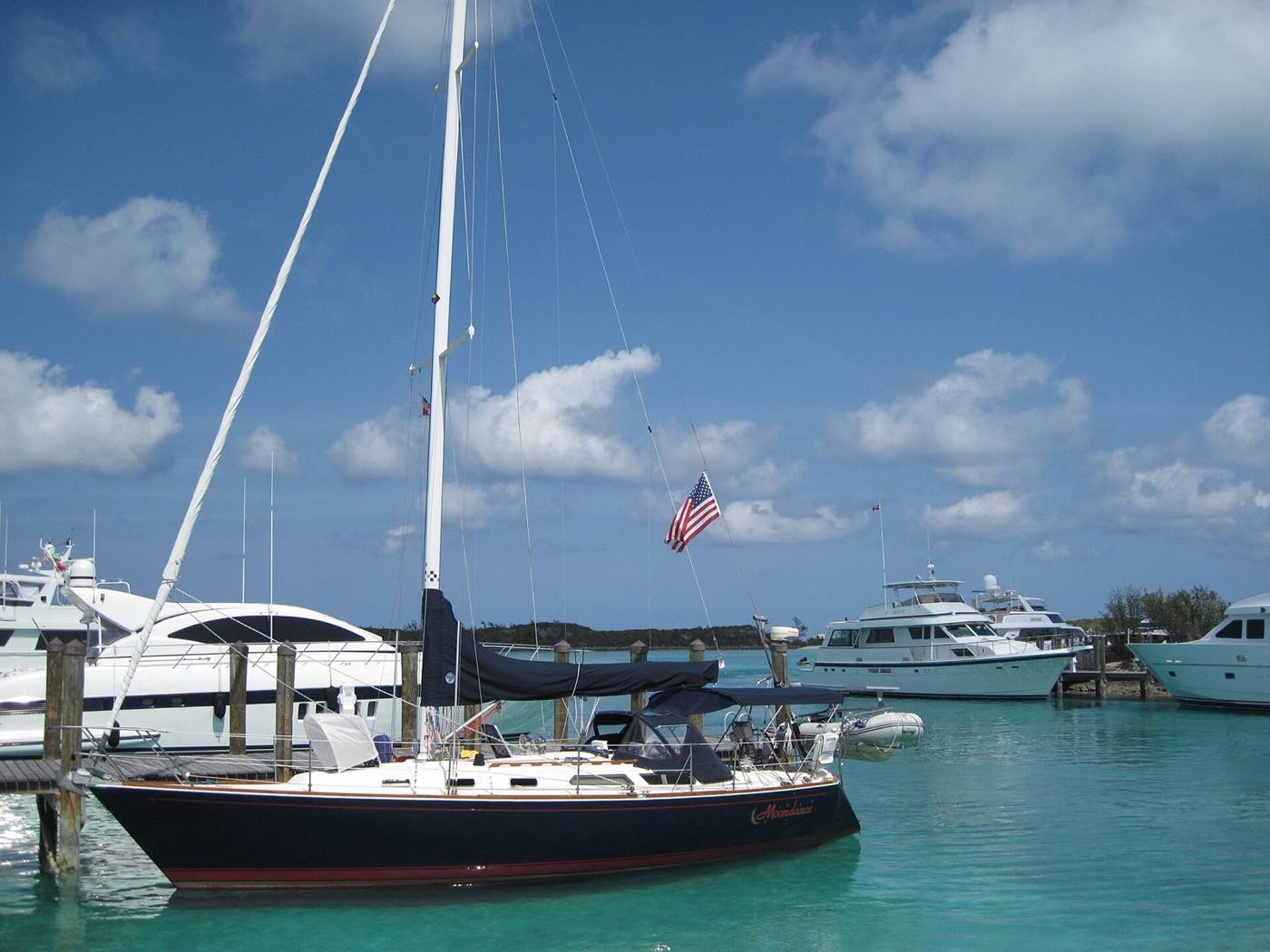 Sailboat and motor yachts tied to docks in clear turquoise Bahamian marina water