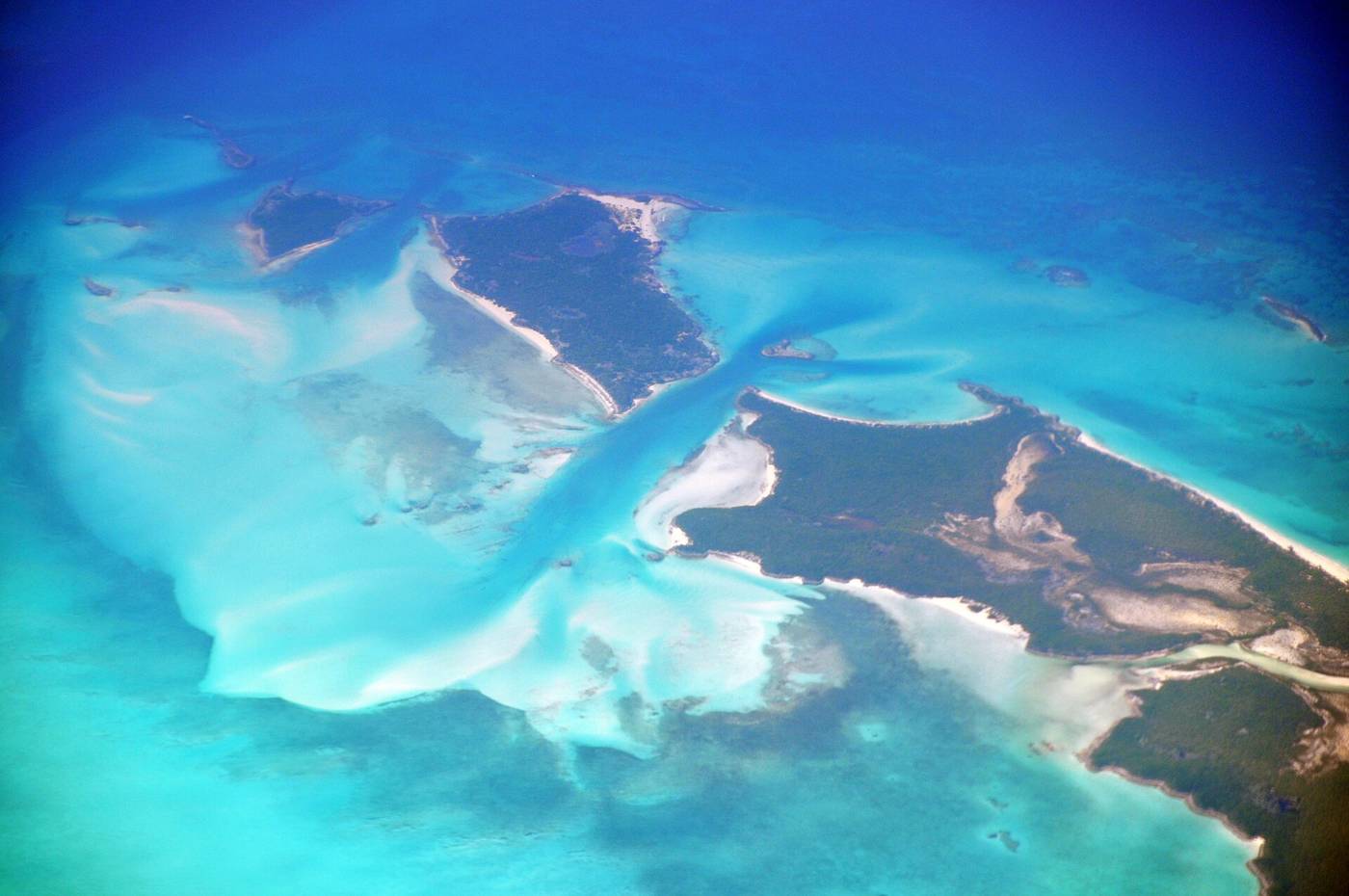 Aerial view of a sandy tidal channel running between two cays into turquoise shallows