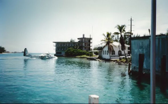 Turquoise harbour water at Bimini with a seaplane taking off beside waterfront buildings