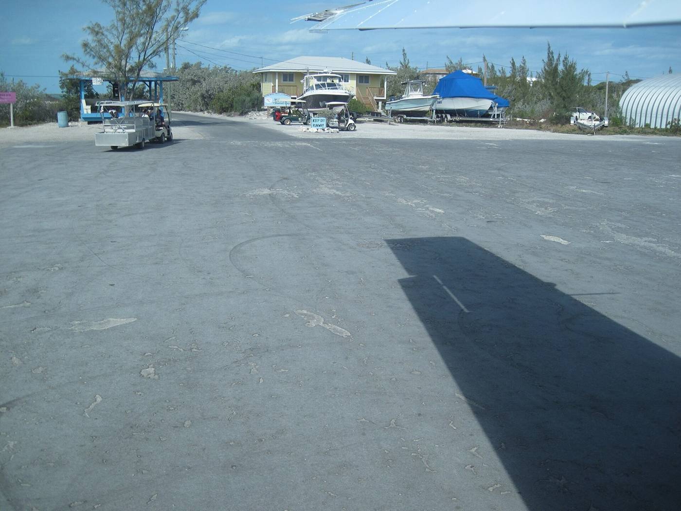 Staniel Cay airstrip apron with a Keep Off Runway sign and golf carts