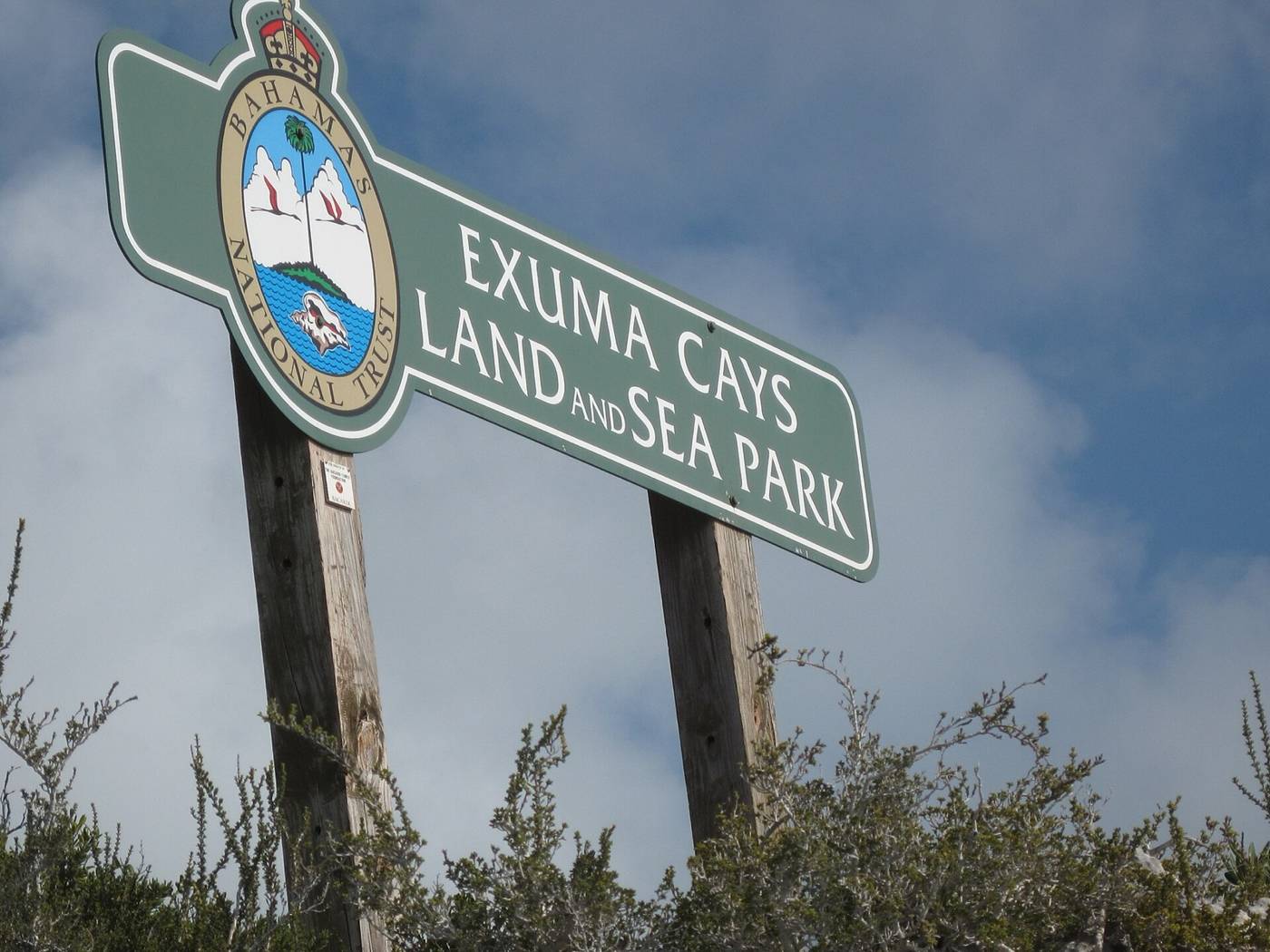 Green Exuma Cays Land and Sea Park sign with Bahamas National Trust seal on wooden posts