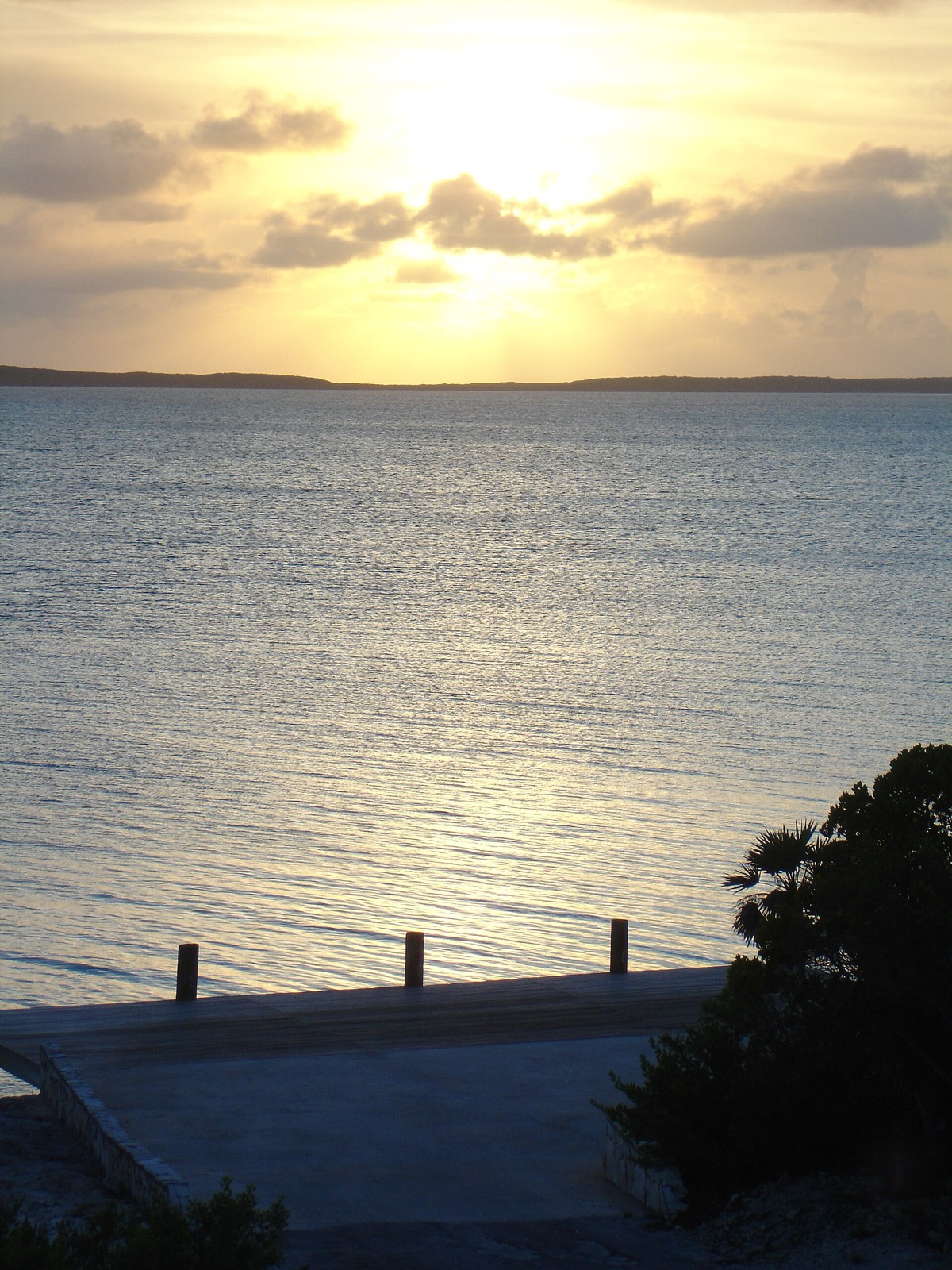 Sunset over calm water beside a concrete dock on Lee Stocking Island (Williams Cay)