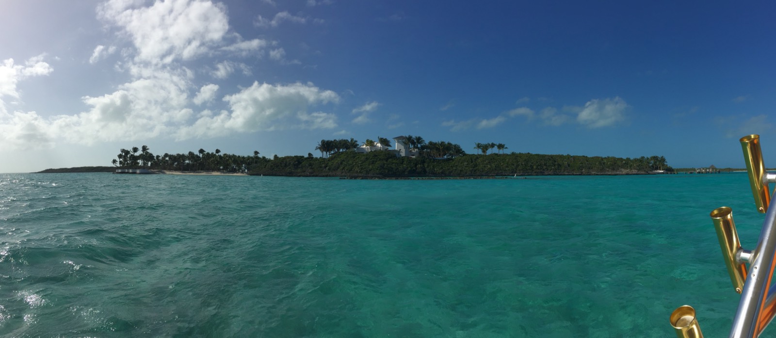 Wide panorama of turquoise Exuma water with a palm-fringed cay on the horizon