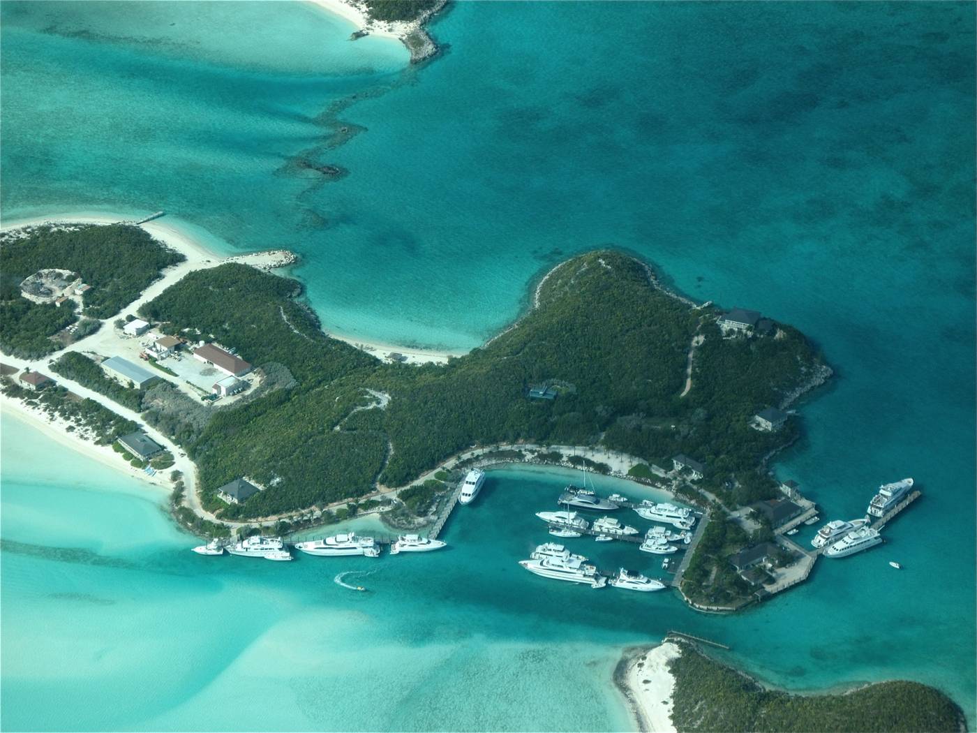 Aerial view of a marina with white yachts on turquoise Exuma water