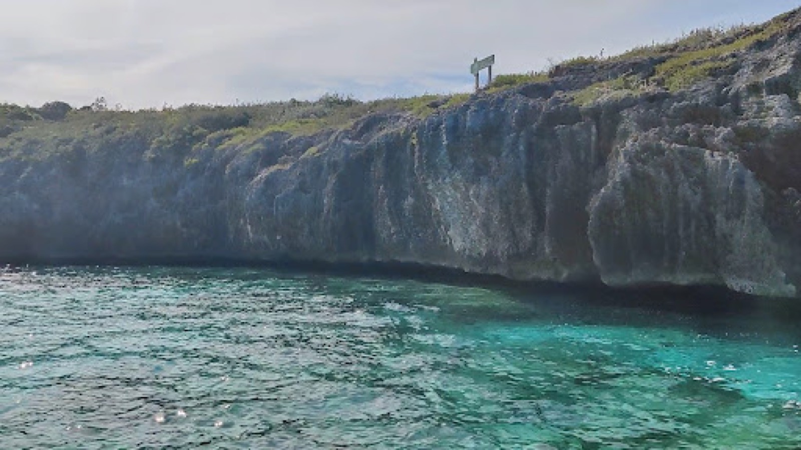 Cliff face of the Rocky Dundas limestone wall with a small sign on the clifftop