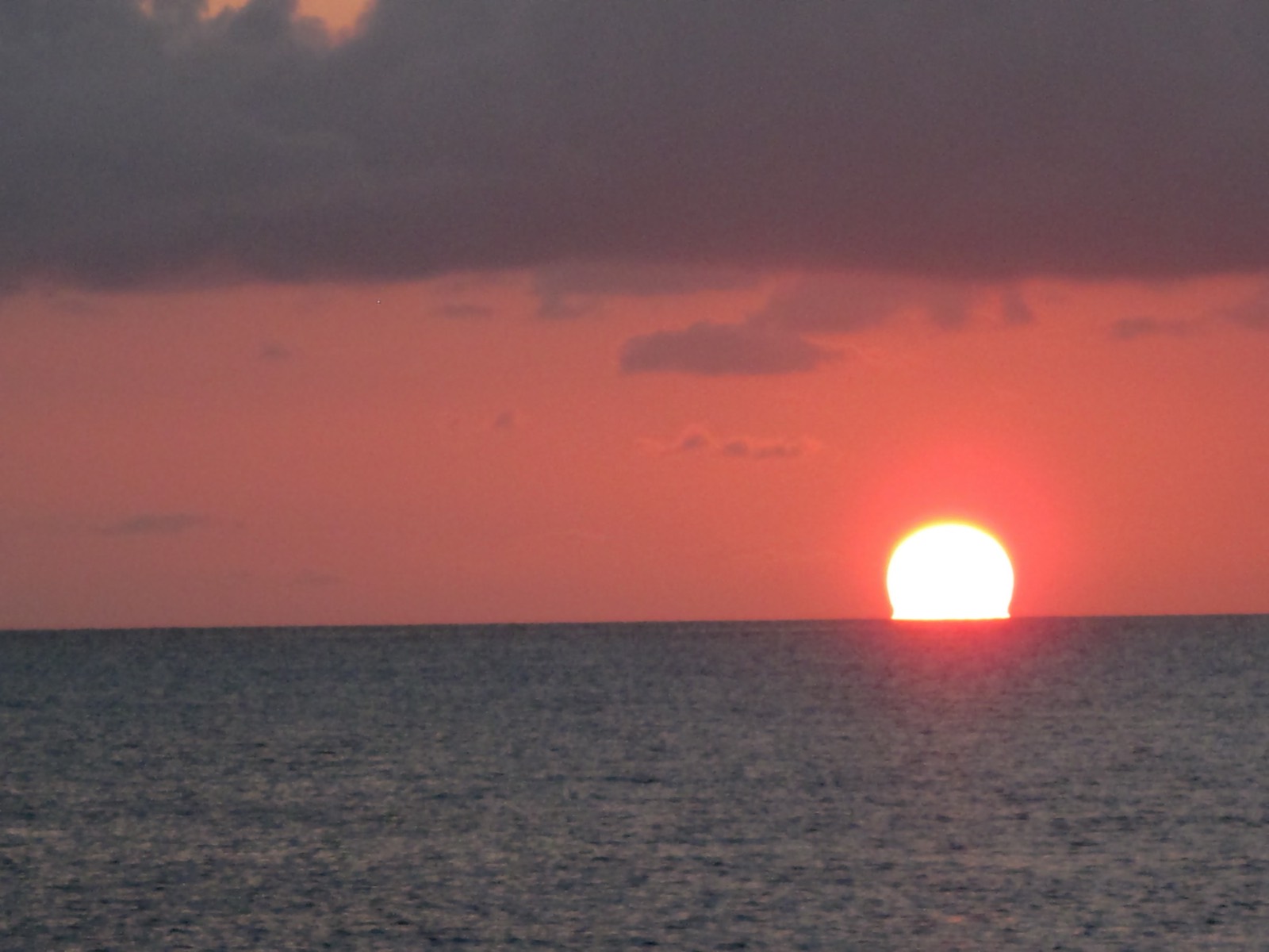 Low red sun setting over calm open water near Staniel Cay