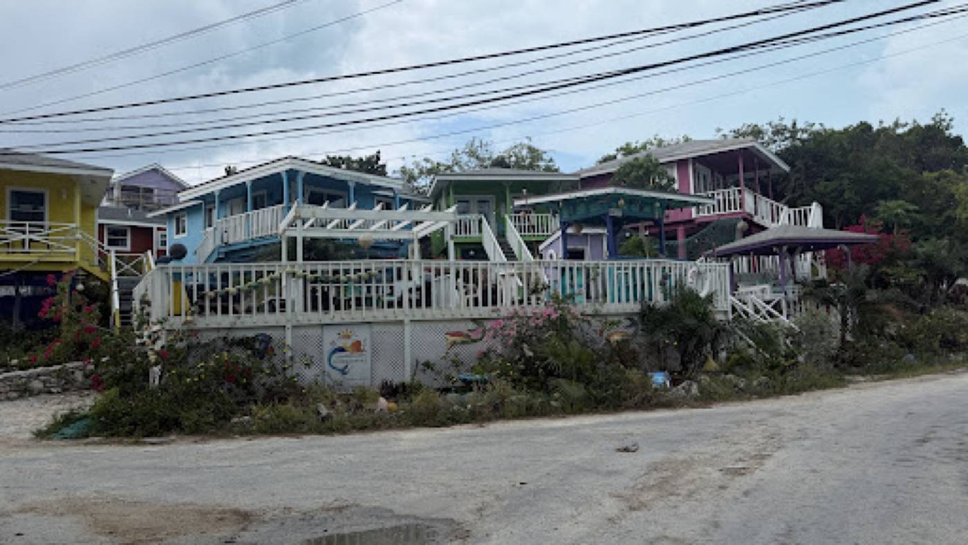 Painted guesthouses with white deck railings along a Staniel Cay roadside