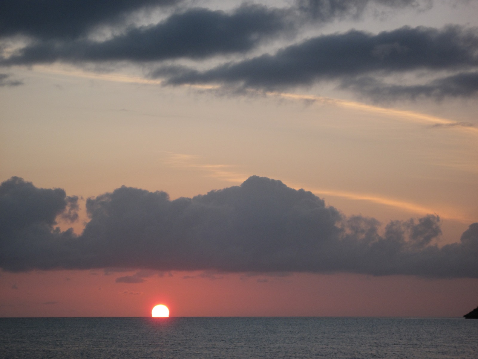 Sunset over the open sea at Staniel Cay, with dark clouds and a red horizon