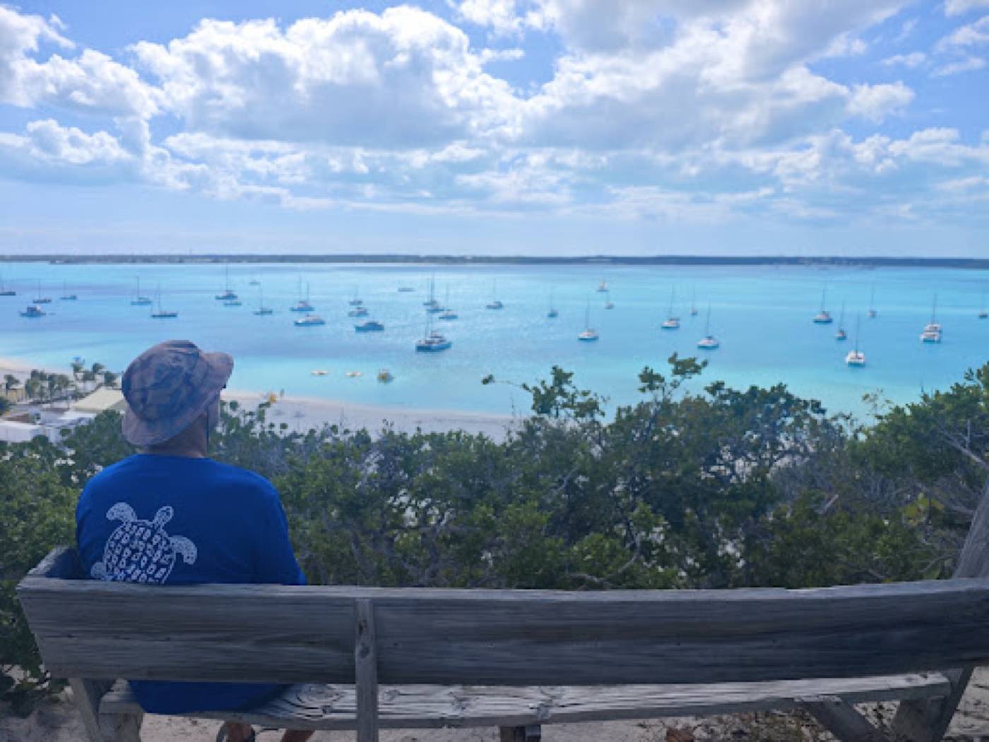 Bench on a hilltop overlooking a sailboat mooring field and a sandy beach, Stocking Island