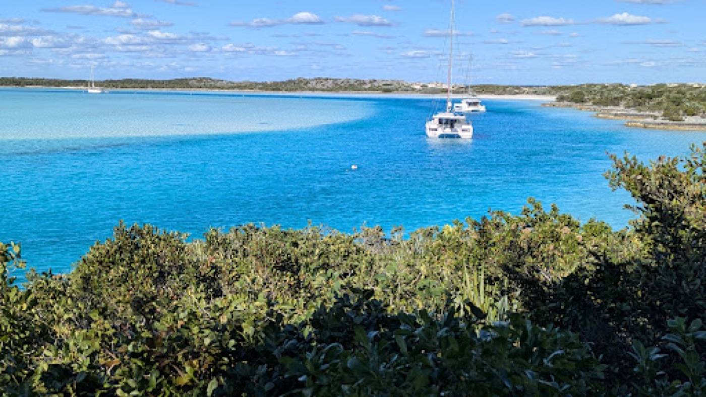 Sailboats and a catamaran at anchor in a turquoise bay